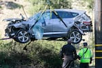 A crane is used to lift a vehicle following a rollover accident involving golfer Tiger Woods, Tuesday, Feb. 23, 2021, in the Rancho Palos Verdes suburb of Los Angeles. Woods suffered leg injuries in the one-car accident and was undergoing surgery, authorities and his manager said.