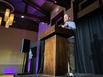 In this photo, Kevin Dolan stands behind a wooden lectern as he speaks to Natal Con attendees.