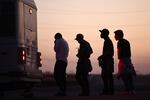 Immigrants seeking asylum wait to board a bus to a U.S. Border Patrol processing center, after crossing into Arizona from Mexico, on Thursday in Yuma, Ariz.