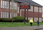 FILE: A woman and child walk past a North Salem High School in Salem, Ore., March 31, 2020, which like all schools in Oregon was closed at that time because of the coronavirus. In the Salem-Keizer School District, 81.5% of migrant students in the Class of 2022 graduated. That’s a more than 10-point increase from the previous year.