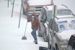 A person carries a broom after brushing snow off a car Monday, Feb. 15, 2021, in St. Louis. Missouri is being hit by a winter storm bringing snow and brutally cold temperatures. (AP Photo/Jeff Roberson)