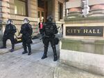 Riot police guard City Hall as protesters lobbed water bottles. A few officers used pepper spray.
 