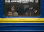 Children look out from a carriage window as a train prepares to depart from a station in Lviv, Ukraine, on March 3, 2022. The U.N. says more than 8 million Ukrainians fled to Europe since the start of the invasion.