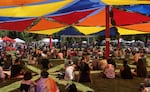 Eugene pride attendees rest under a colorful shade structure.