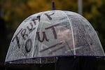 A protester stands in the rain at a rally at Elizabeth Caruthers Park in Portland, Ore. on Saturday, Oct. 25, 2025. A crowd of about 100 people marched from the park to the Immigration Customs and Enforcement building in the afternoon.
