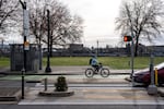 A biker and driver pass by Mill Ends Park at left, the smallest park in the United States and once the smallest park in the world, which occupies part of a crosswalk in Portland, Ore., on March 9, 2026.