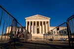 A classical style federal building with temporary fencing set up in front to create a pathway towards its stairs