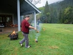 Joe Scott, left, and Aliyah Zweig, right, prepare to toss flaming pitch-covered pine cones to demonstrate a cultural fire ignition technique over a wet lawn at the Siskiyou Field Institute in Selma, Ore., April 11, 2026.