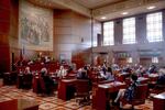 People sit at desks on the floor of the Oregon Senate in the state Capitol building.