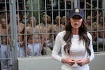 As prisoners stand looking out from a cell, U.S. Homeland Security Secretary Kristi Noem speaks during a tour of the Terrorist Confinement Center in Tecoluca, El Salvador, March 26, 2025.