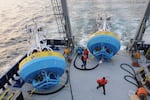 In this 2021 image provided by Woods Hole Oceanographic Institution, workers walk near buoys used to gather data at Pioneer New England shelf off the coast of Martha’s Vineyard, Mass.