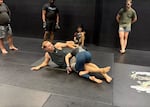 Adam Fugitt, in a black tank top, uses his background in wrestling, as well as his training in other fighting styles, to adapt to his opponent’s strategy.