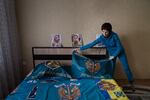 Natalia Kucherenko drapes a flag over the bed in her son's room in the Sumy region of Ukraine. He was captured by Russian forces in Mariupol and Kucherenko waits for him to be returned.
