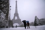 People walk near the Eiffel Tower during a snowfall Wednesday, Jan. 7, 2026 in Paris.