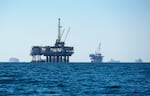 FILE - Cargo vessels are seen anchored offshore, sharing space with oil platforms, before heading into the Los Angeles-Long Beach port on Oct. 5, 2021.