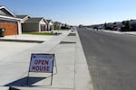 A small paper sign advertises an open house in an empty suburban-style neighborhood.