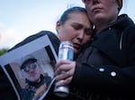 People embrace as one holds the photo of a loved one, who was still missing at that time, in the Nippon Dynawave Packaging Co. chemical disaster during a vigil for the victims of the tragedy at R.A. Long Park in Longview, Wash., on May 26, 2026.