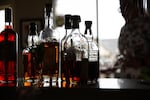 Joshua Madrid pulls spirits and glasses from his pantry before hosting a virtual happy hour Saturday, May 9, 2020, in Portland, Ore.