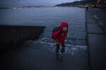 Ely Thomas, 7, runs from water spilling over stairs during a King Tide at Alki Beach Park on Friday, January 5, 2018, in West Seattle.