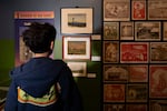 A museum visitor stands in front of watercolor paintings created by Sadao Mizuno (center) while being incarcerated at Minidoka concentration camp, on Feb. 20, 2026 at the Japanese American Museum of Oregon in Portland.
