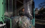 A worker carries used drink bottles and cans for recycling at a collection point in Brooklyn, New York. Three decades of recycling have so far failed to reduce what we throw away, especially plastics.