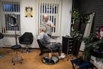 Yevhen Shcherbyna, a hairdresser in Dnipro, colors a woman's hair at his salon downtown. He hears from many clients that they're worried their family members will be conscripted.