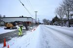 A construction crews works alongside an empty road. 