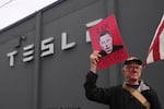 A man holds a sign with Elon Musk's face and the slogan "I am stealing from you" on it during a protest against Musk and Tesla on Saturday in Seattle.