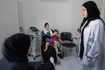 Mariam waits and plays with her grandmother during her mother's physical therapy appointment.