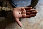 An soldier with the HTS shows some of the captagon pills that they found at the facility.