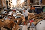 A man walks through a debris-covered street after flash floods hit eastern Spain on October 30, 2024. Climate scientists say global warming makes extreme rain events like it more likely.