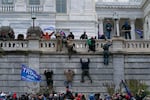 FILE - Supporters of President Donald Trump climb the west wall of the the U.S. Capitol in Washington as they try to storm the building on Jan. 6, 2021, while inside Congress prepared to affirm President-elect Joe Biden's election victory.