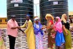 GAVE Founder Heather Coleman Cox (red shirt and hat) meeting with villagers next to the water tanks