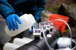 Penaluna pours river water into a filtering device to extract particles for eDNA analysis.