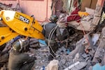 Rescuers use a small excavator to search for survivors under the rubble of a collapsed house in Moulay Brahim, Al Haouz province.
