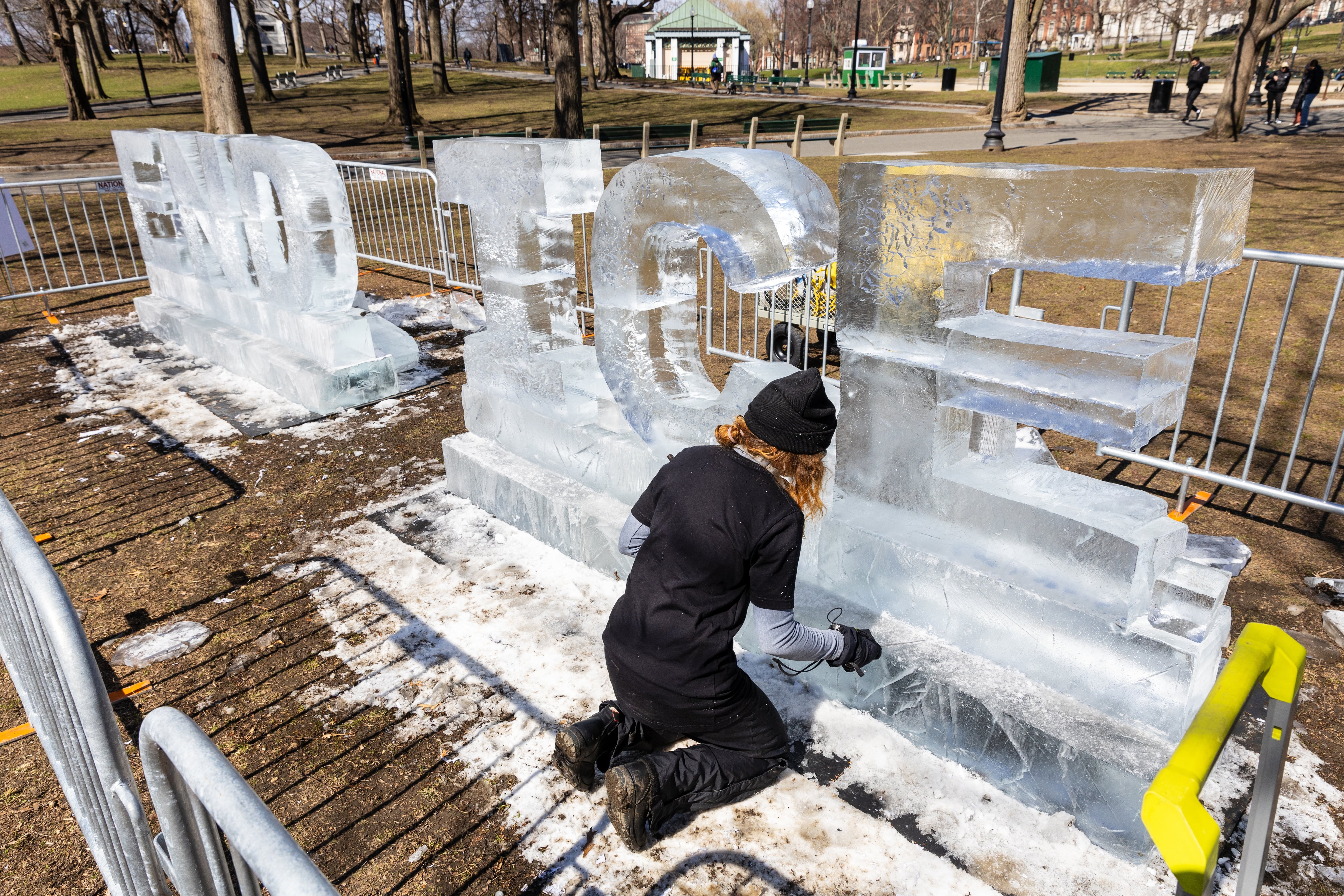 Kat Carves works on a ice sculpture that says 'End Ice' ahead of the rally on the Boston Common in Boston.
