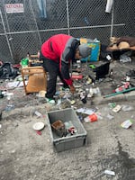 Randy Hauser hurries to gather up his possessions under an overpass south of Market Street, as city workers approach for a sweep.