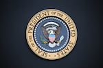 The presidential seal pictured, with a bald eagle front and center. 