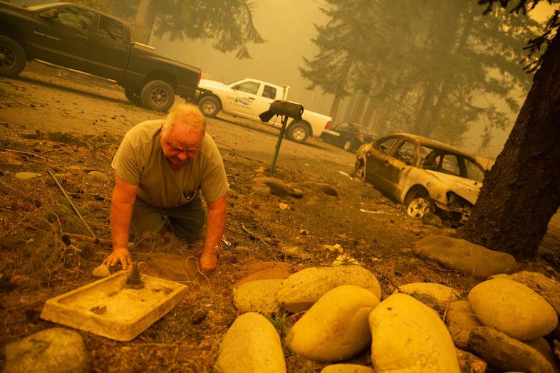 Gary Benthin works to shut off water to homes destroyed by the Santiam Fire near Gates, Ore., Sept. 9, 2020. Firefighters were struggling with a water shortage.