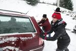 Friends help push Jacey Bustad's car out of a snow bank after it got stuck halfway up Mt. Scott Wednesday night.