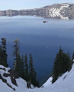 A helicopter lifts a man who fell an estimated 1,000 feet down the Crater Lake caldera on Sunday, May 21, 2017.