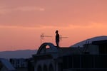 A man stands on the roof of a building while watching the horizon in Tehran on June 16. Iran's state broadcaster was briefly knocked off the air by an Israeli strike and explosions rang out across Tehran that day.