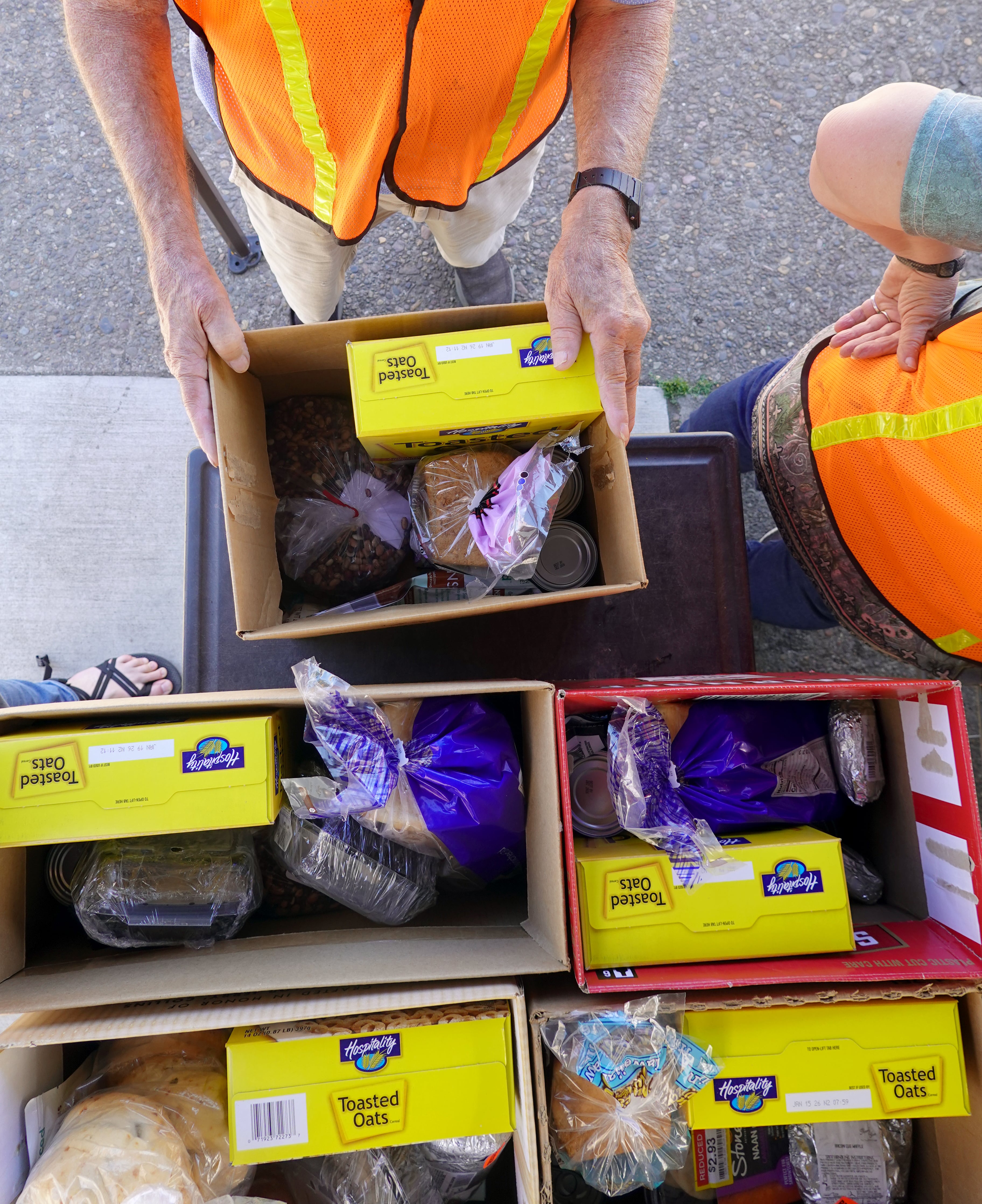 A volunteer passes out food boxes in Sheridan, Ore., at the Grand Sheramina Food Bank. Most of the people in line have food stamps, but still struggle to afford their groceries, volunteers said.