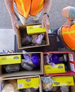 A volunteer passes out food boxes in Sheridan, Ore., at the Grand Sheramina Food Bank. Most of the people in line have food stamps, but still struggle to afford their groceries, volunteers said.