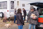 In a photo provided by Mountain View Community Development, case manager Stephanie Buechert (left) delivers food and talks with Don, a former participant at a safe parking site in Redmond, Ore., in March 2025.