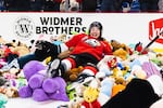 A Portland Winterhawks player lies on top of a pile of plushies at the annual Teddy Bear Toss game on Dec. 10, 2022.