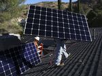 Workers install solar panels on a home in California in 2023.