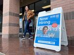 A customer walks by a "Now Hiring" sign posted in front of a store in Novato, Calif., on April 7, 2023.