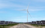 FILE - Solar panels and wind turbines work to create clean electric power at the Wheatridge Renewable Energy Facility near Lexington, Ore., May 24, 2022. 