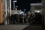 Federal police wait inside the gate of the Immigration and Customs Enforcement processing center south of downtown Portland during protests on Sunday, Oct. 6, 2025.